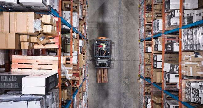 Young warehouse worker sitting in forklift 