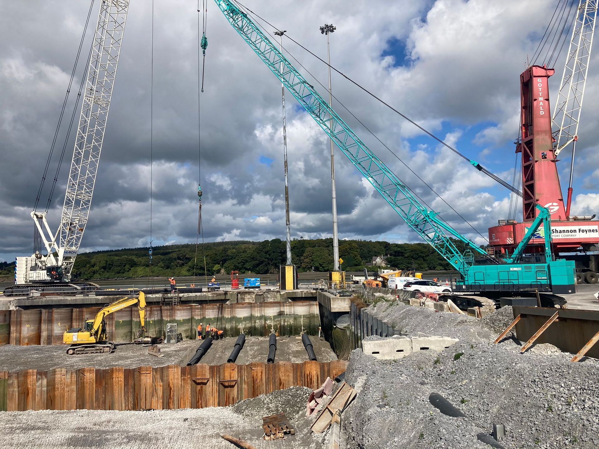 A construction site with a blue crane and a red crane