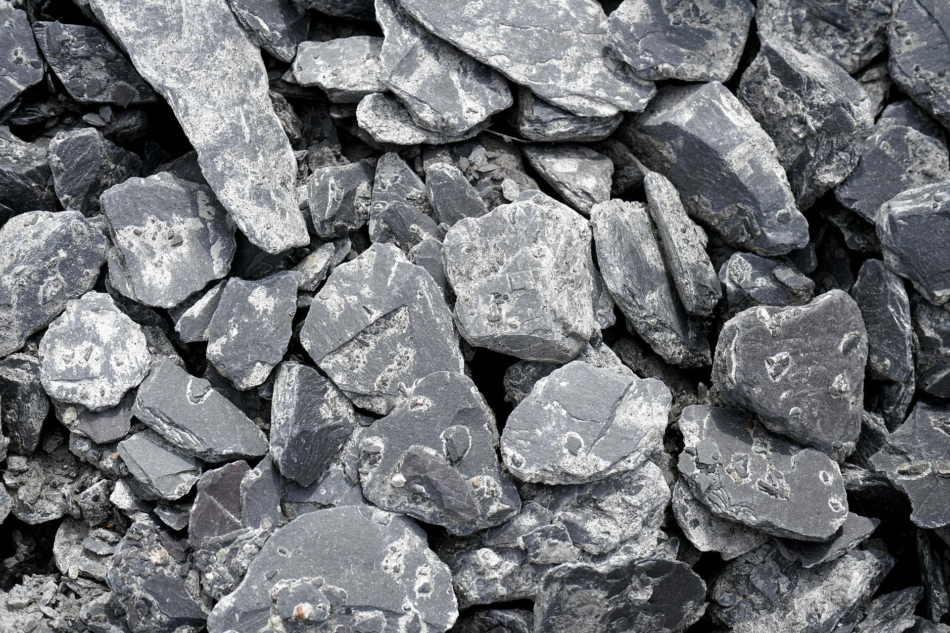 A pile of rocks that look like coal is sitting on the ground.