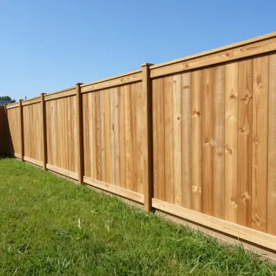 Wooden privacy fence along a grassy yard under a clear blue sky