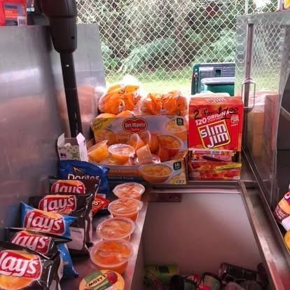 A vending stand display featuring stacks of Lay’s chips, fruit cups, and a box of Slim Jim sticks.