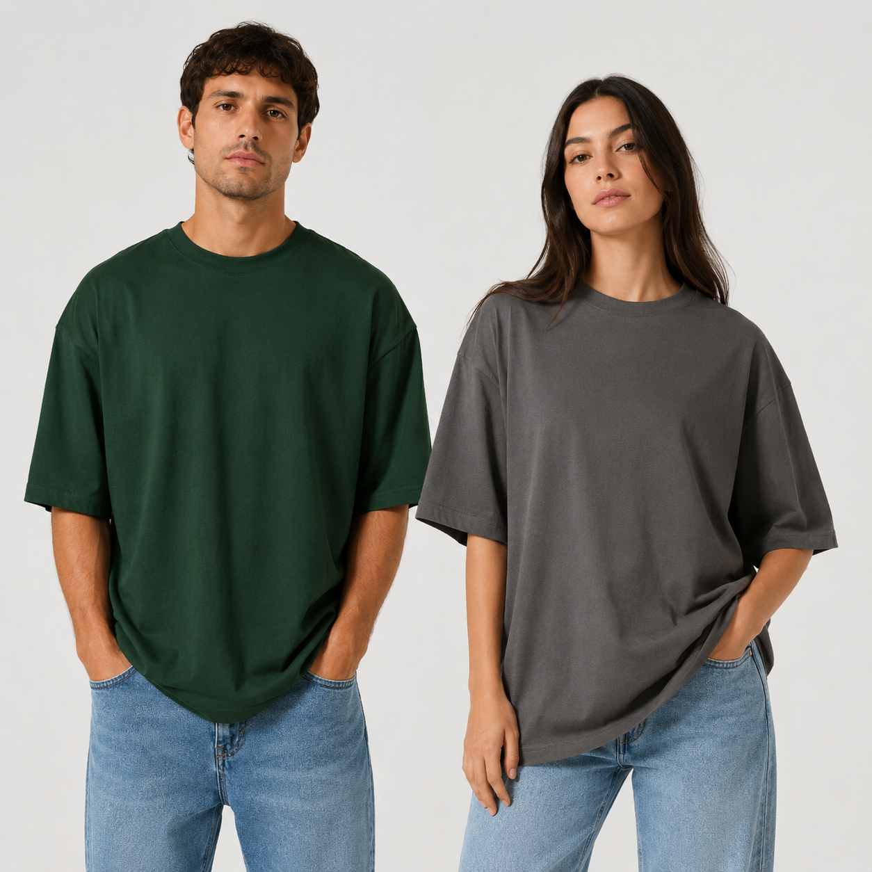 Dos modelos con camisetas extragrandes verdes y grises y vaqueros sobre un fondo liso claro.