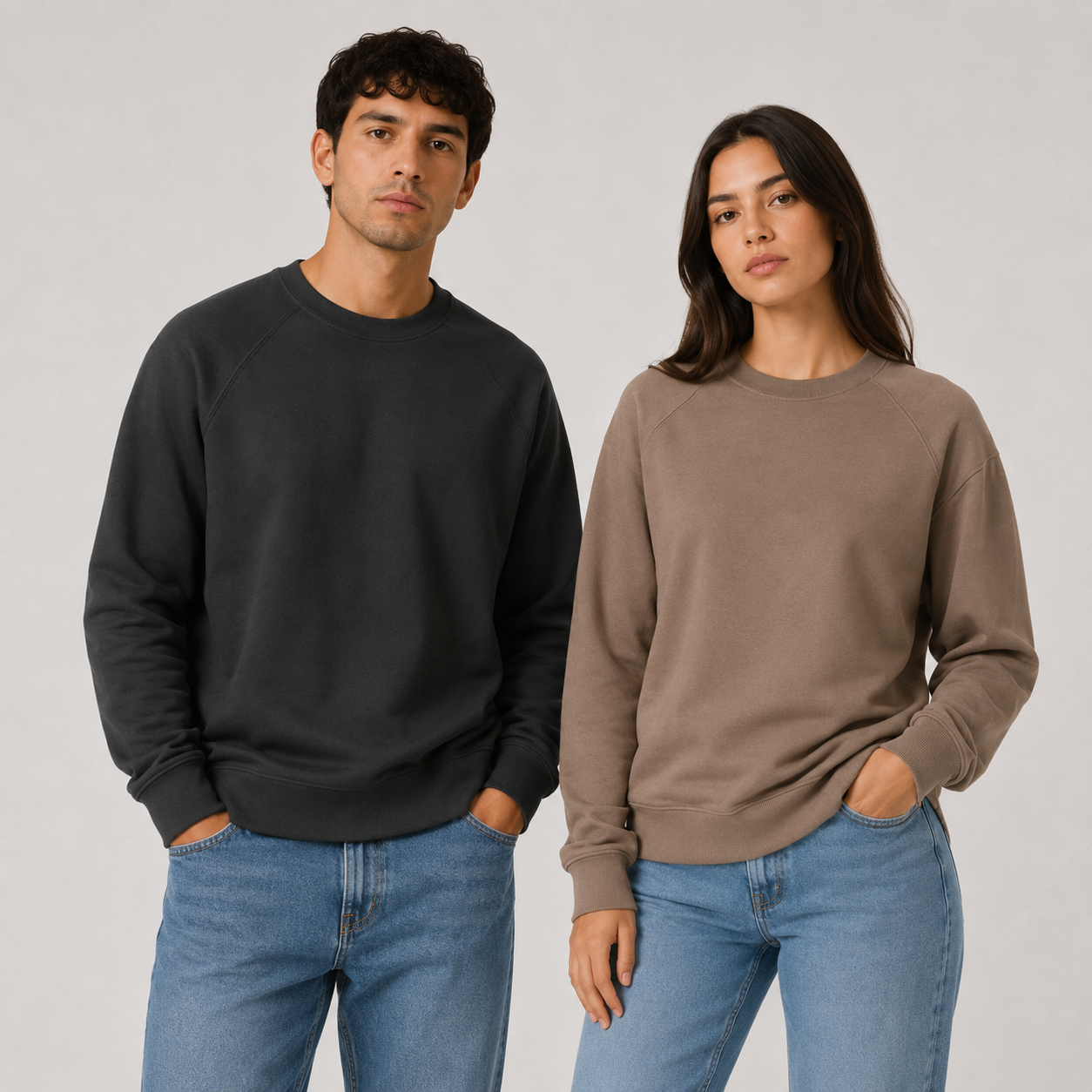 Dos modelos con suéteres informales y jeans sobre un fondo gris claro.