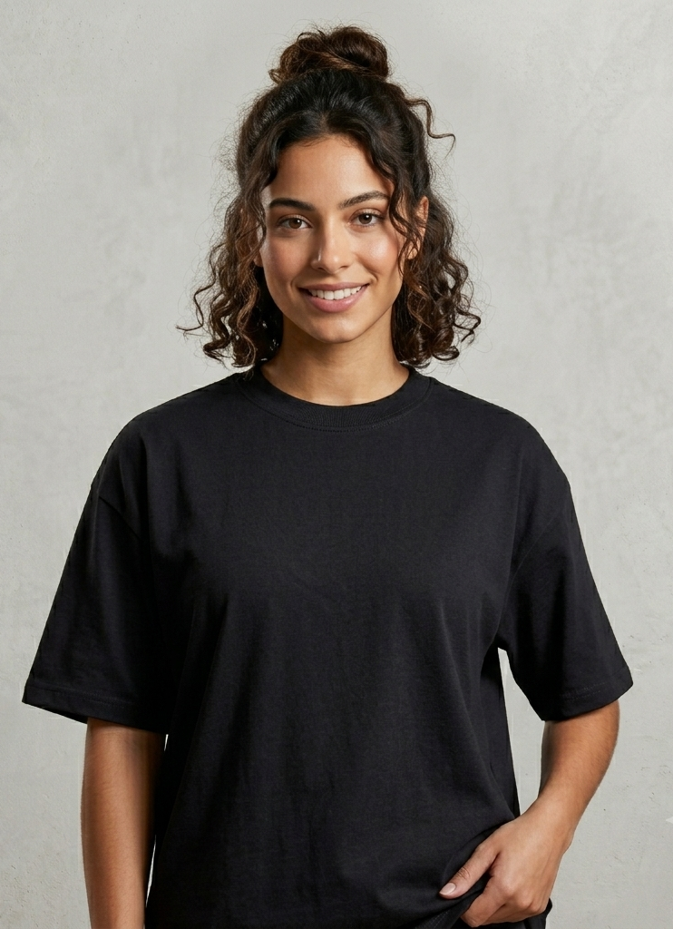 Persona sonriente con una camiseta negra de pie sobre un fondo gris claro.