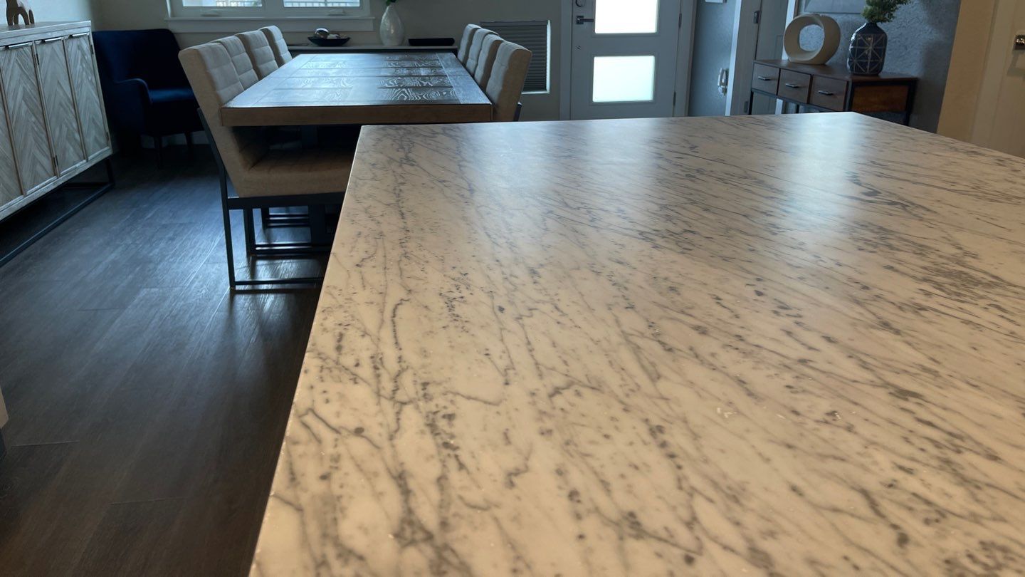 Modern kitchen with a marble island in the foreground and a dining table in the background