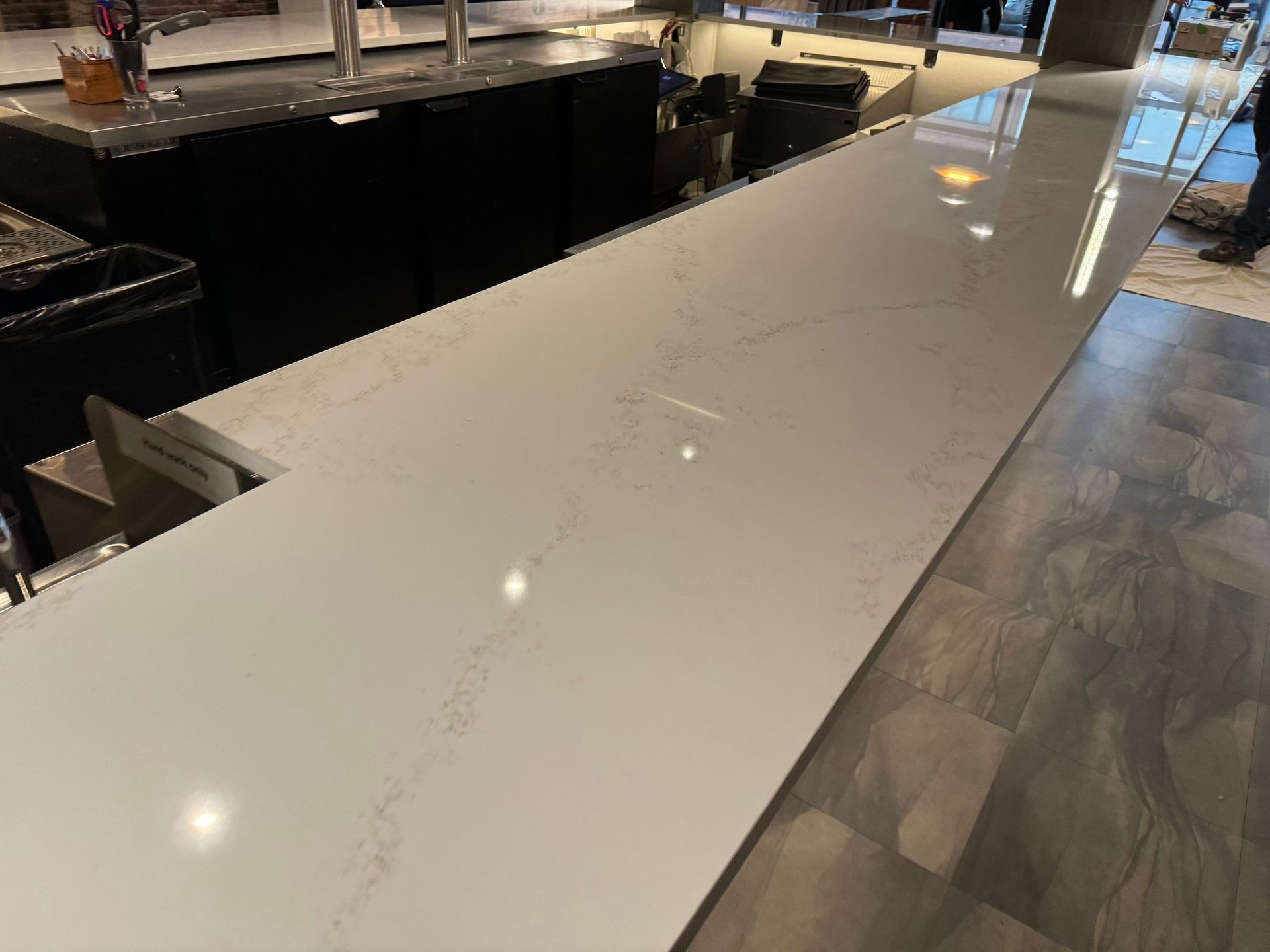 Large white marble kitchen island with dark wood base in a bright modern kitchen