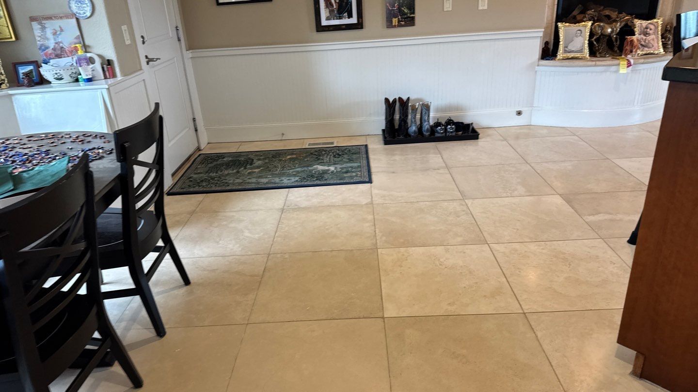 Dining area with beige tile floor, dark table and chairs on left, and white fireplace wall in back.