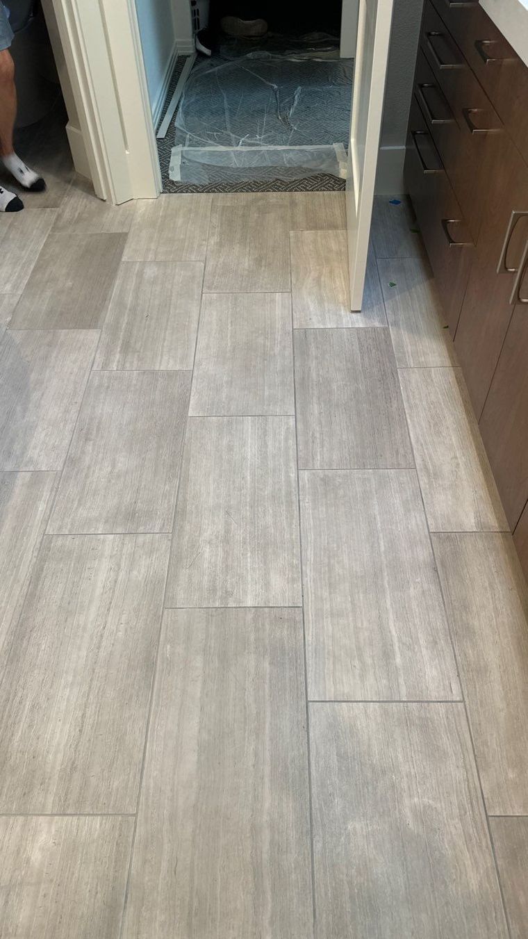 Hallway with light wood flooring leading to an open doorway and cabinets on the right