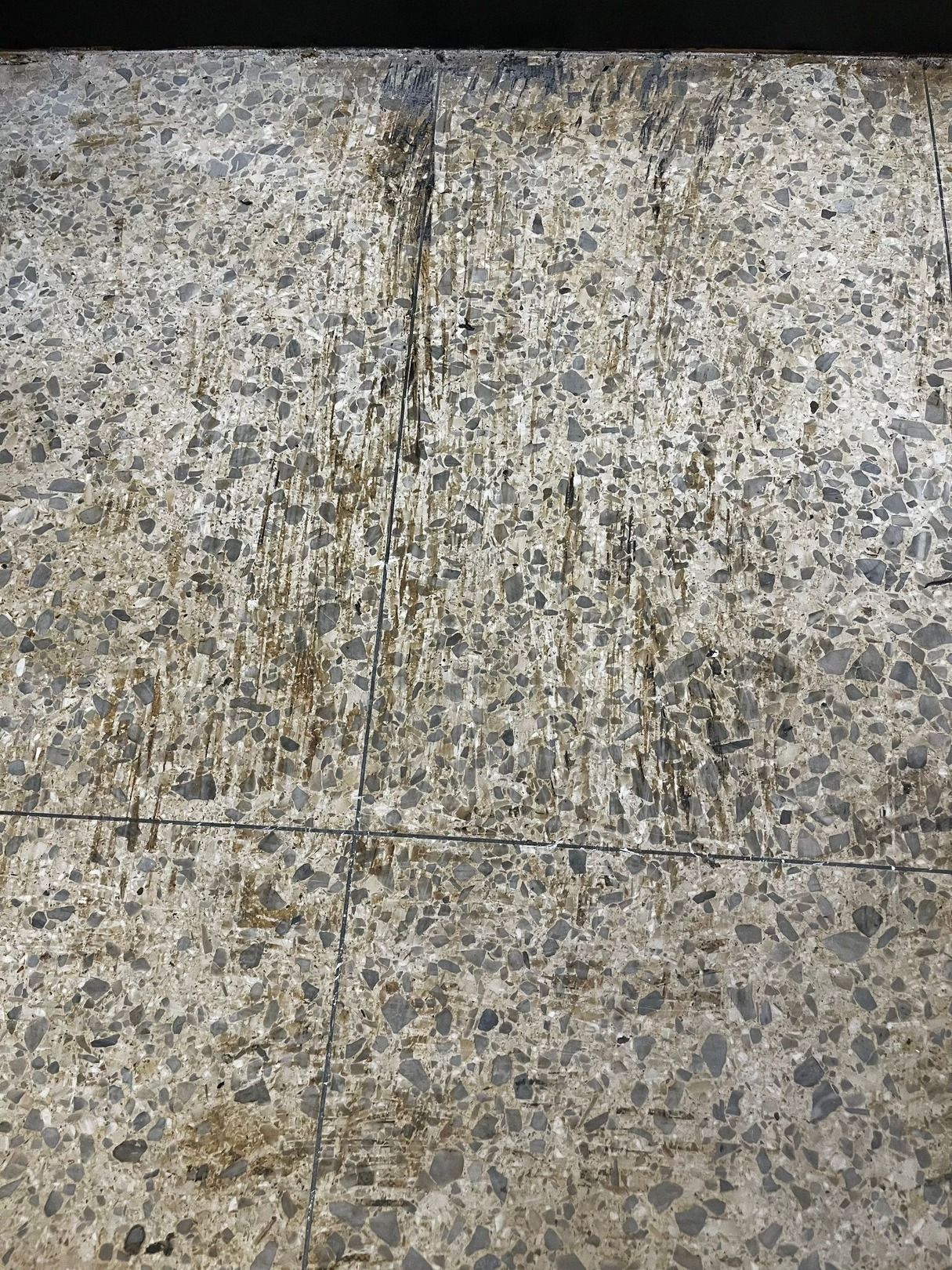 Close-up of speckled gray stone pavement with a seam crossing the center