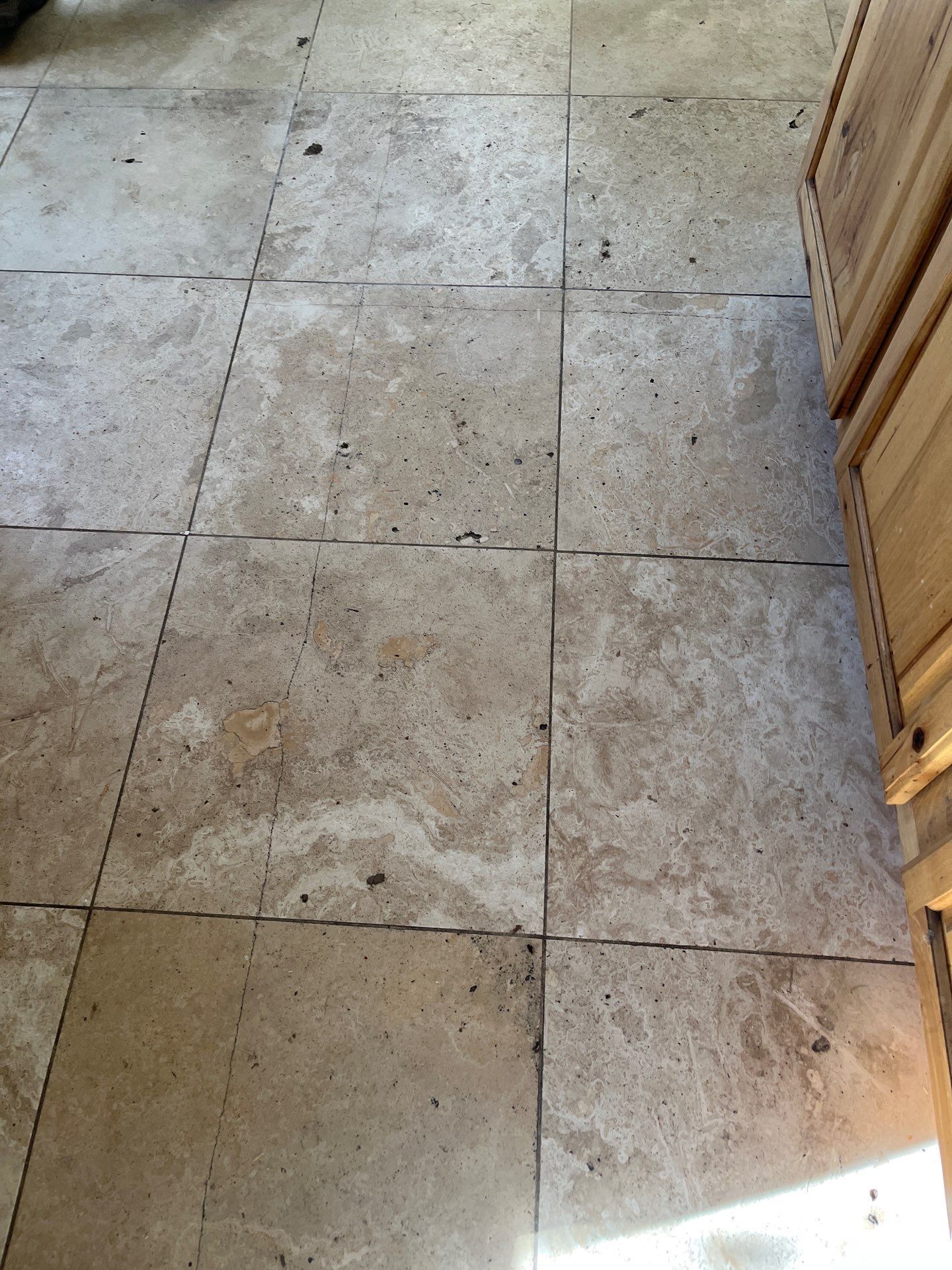 Dusty beige tiled floor with grout lines and sunlight at the lower right edge