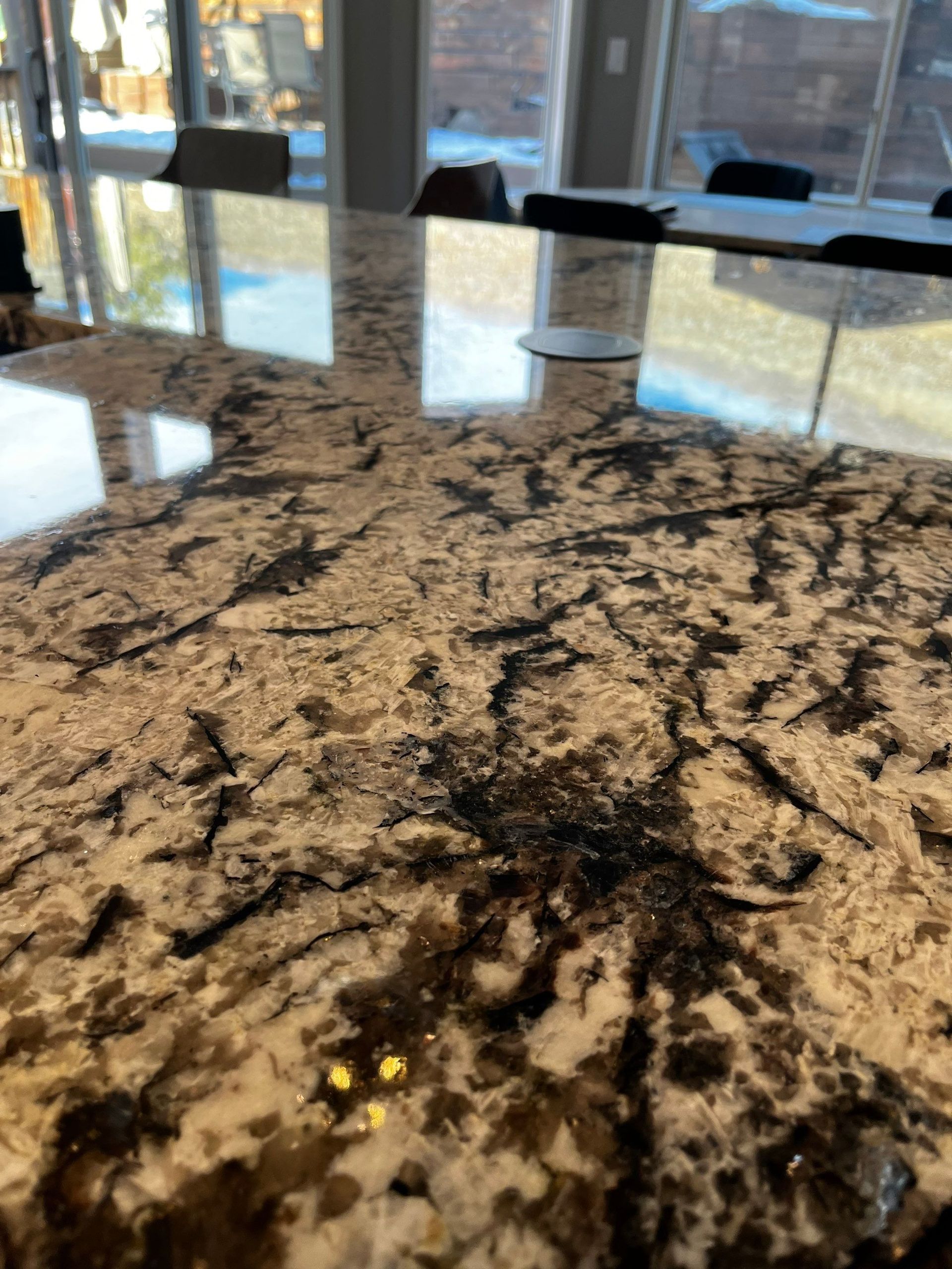 Granite kitchen countertop with a sink and bright window reflections in the background