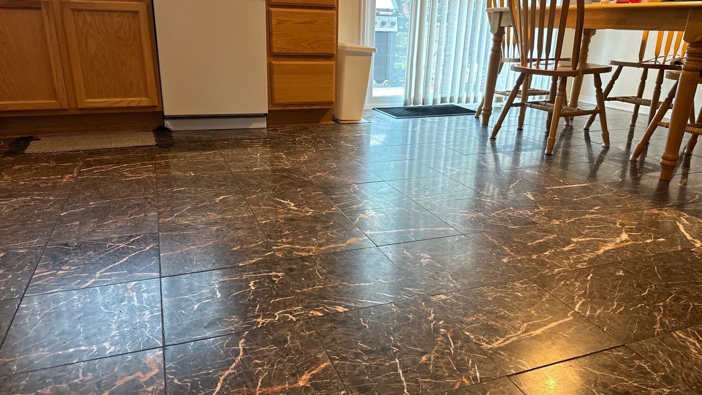 Empty kitchen with dark speckled tile floor, wooden cabinets, and a dining table near sliding glass doors.