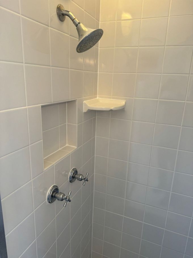 Tiled shower with wall-mounted showerhead, soap dish, and recessed shelf niche