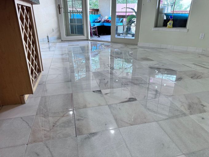 Empty tiled room with glossy marble floor, doors at the far end, and a windowed wall.