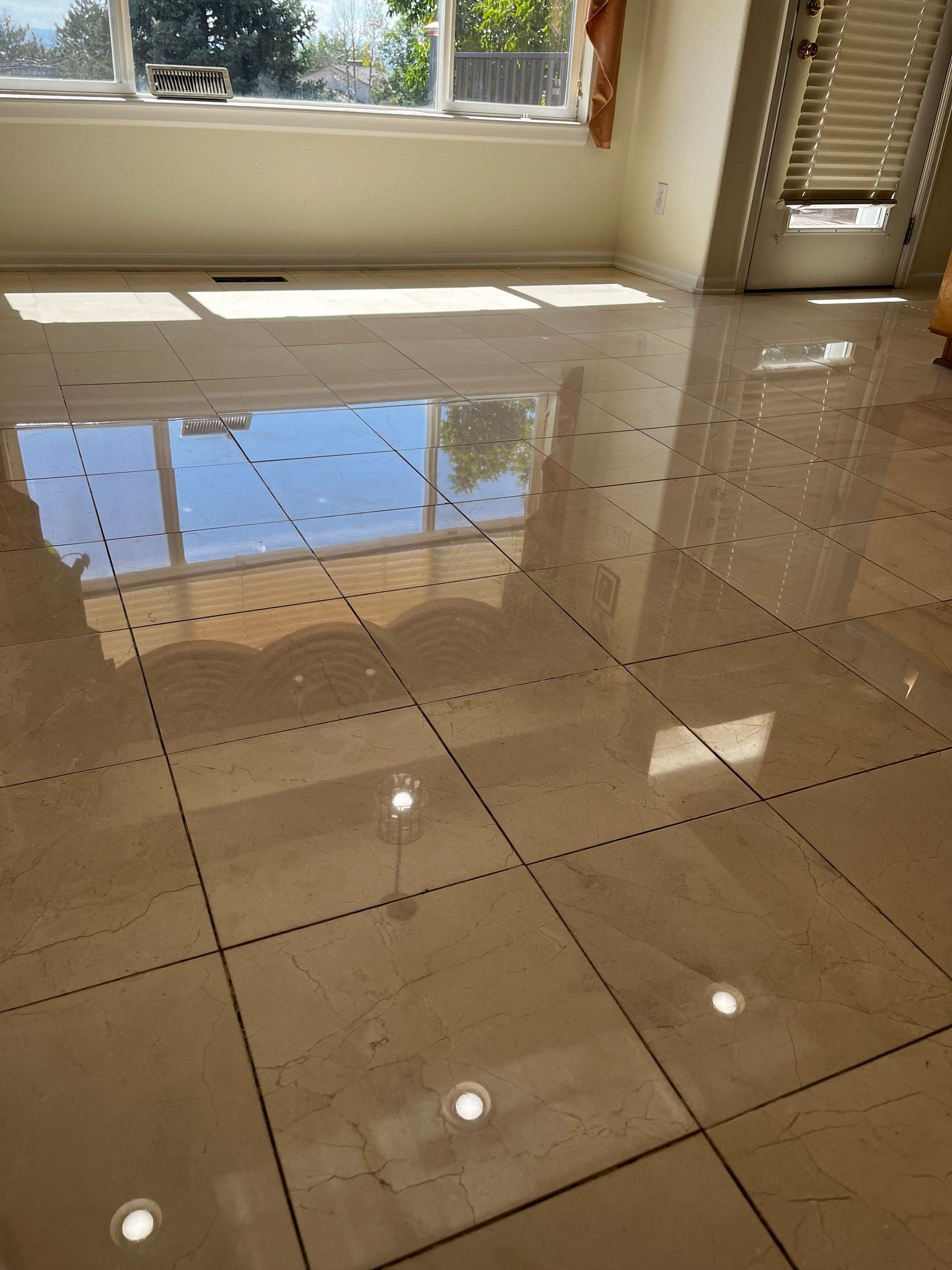 White tiled wall above beige marble baseboard and dark wood floor, with a cardboard box at right edge