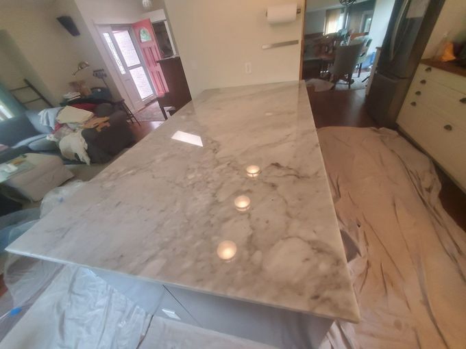 Modern kitchen with a large marble island countertop and light cabinetry in the background