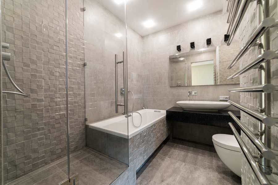 White tiled wall above beige marble baseboard and dark wood floor, with a cardboard box at right edge