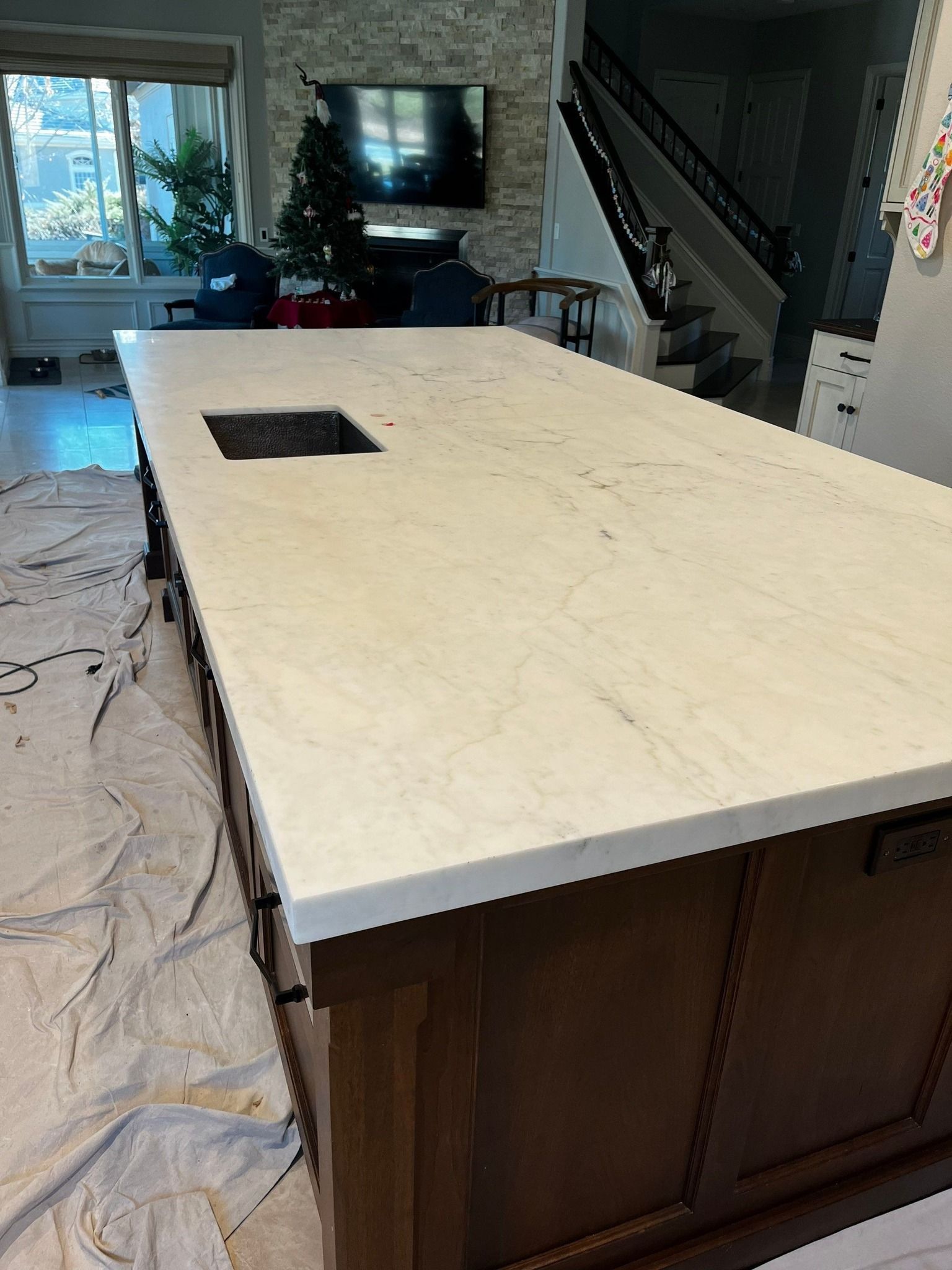 White tiled wall above beige marble baseboard and dark wood floor, with a cardboard box at right edge