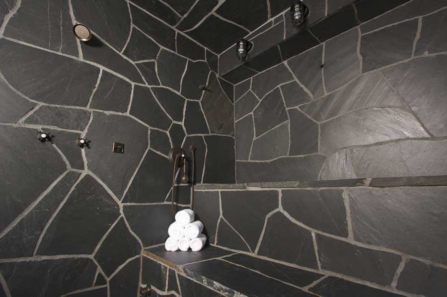 White tiled wall above beige marble baseboard and dark wood floor, with a cardboard box at right edge