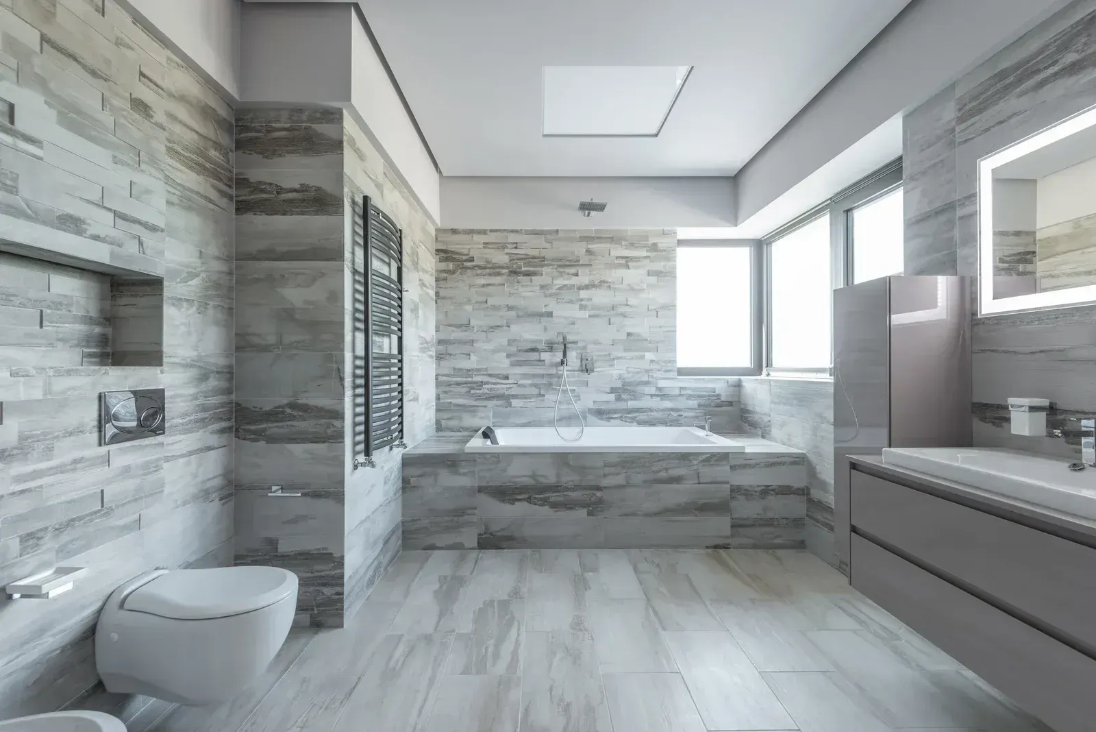 White tiled wall above beige marble baseboard and dark wood floor, with a cardboard box at right edge