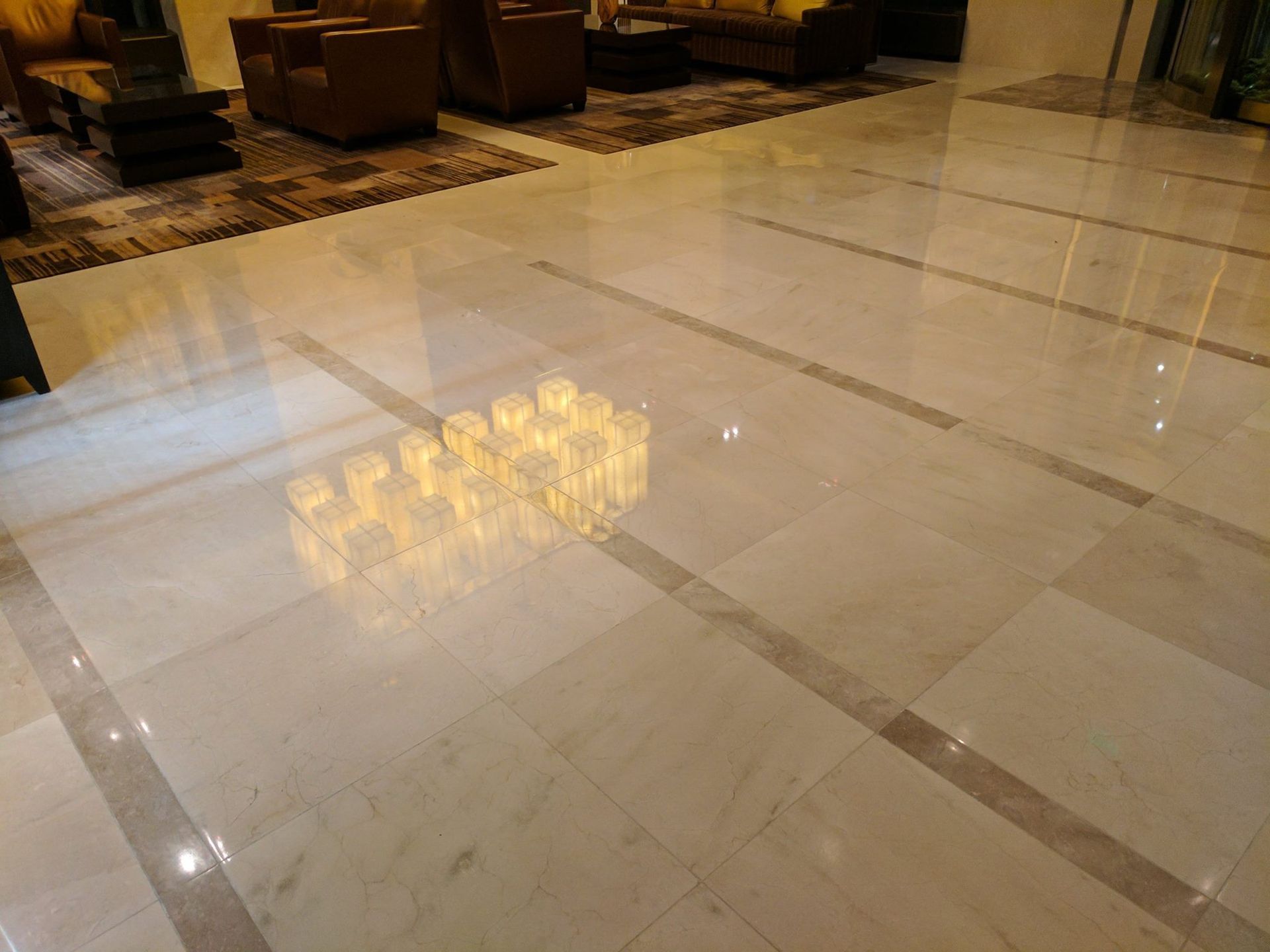 White tiled wall above beige marble baseboard and dark wood floor, with a cardboard box at right edge