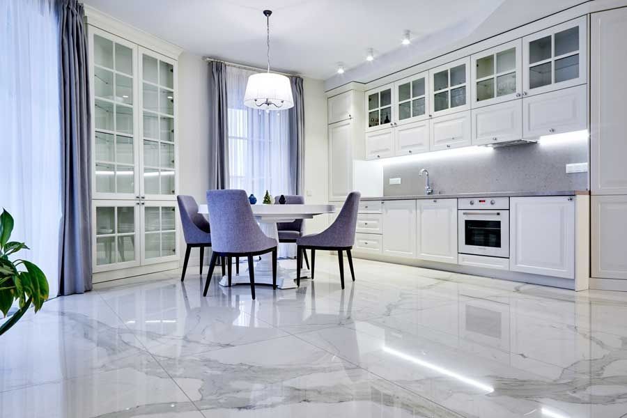 White tiled wall above beige marble baseboard and dark wood floor, with a cardboard box at right edge