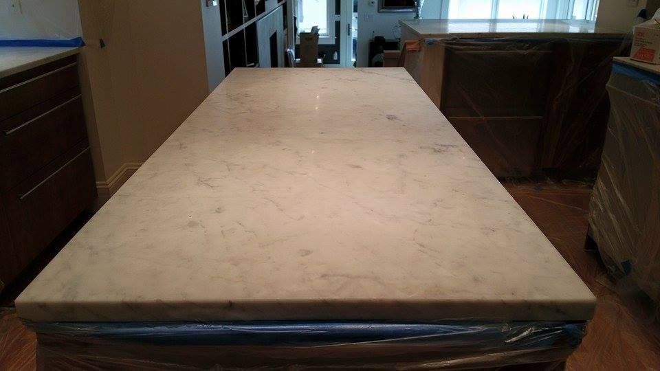 White tiled wall above beige marble baseboard and dark wood floor, with a cardboard box at right edge