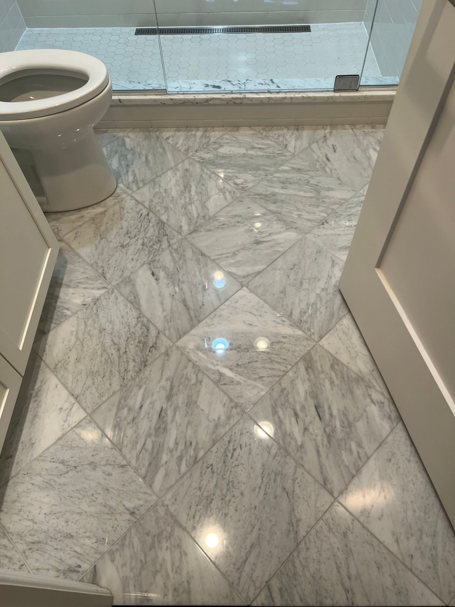 Narrow polished hallway with wood-paneled walls and a glossy tiled floor reflecting light.