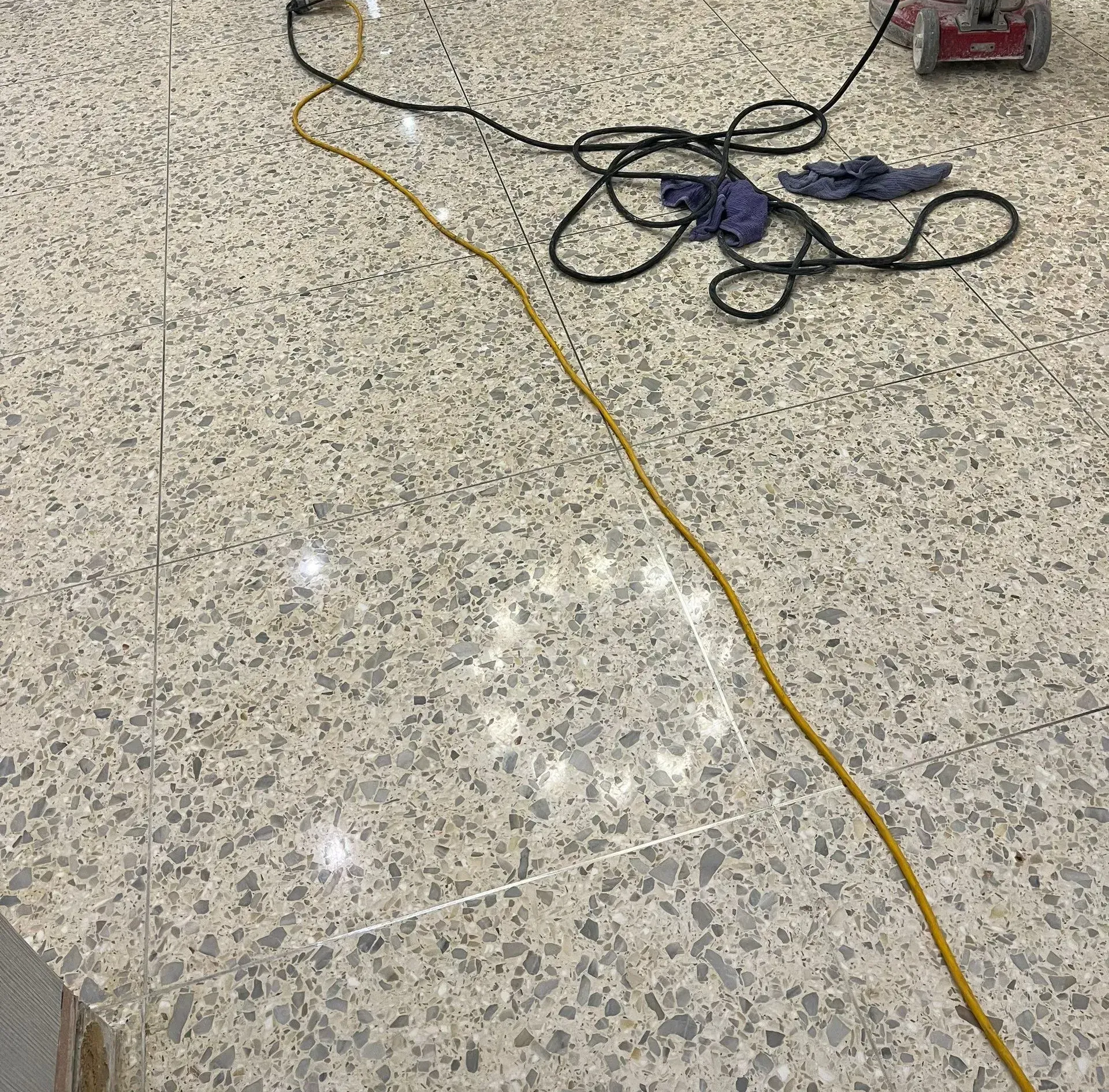 Tangled power cords on a speckled floor, with a yellow extension cord crossing the scene.