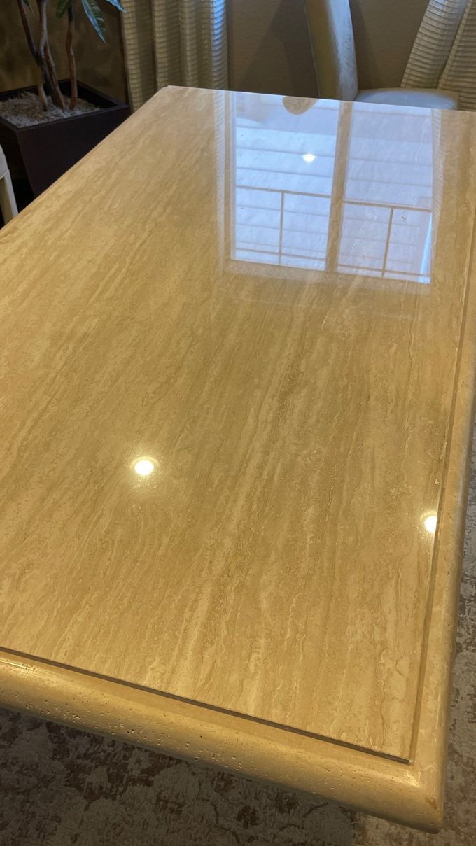 Glossy light wood table surface reflecting a window and curtains