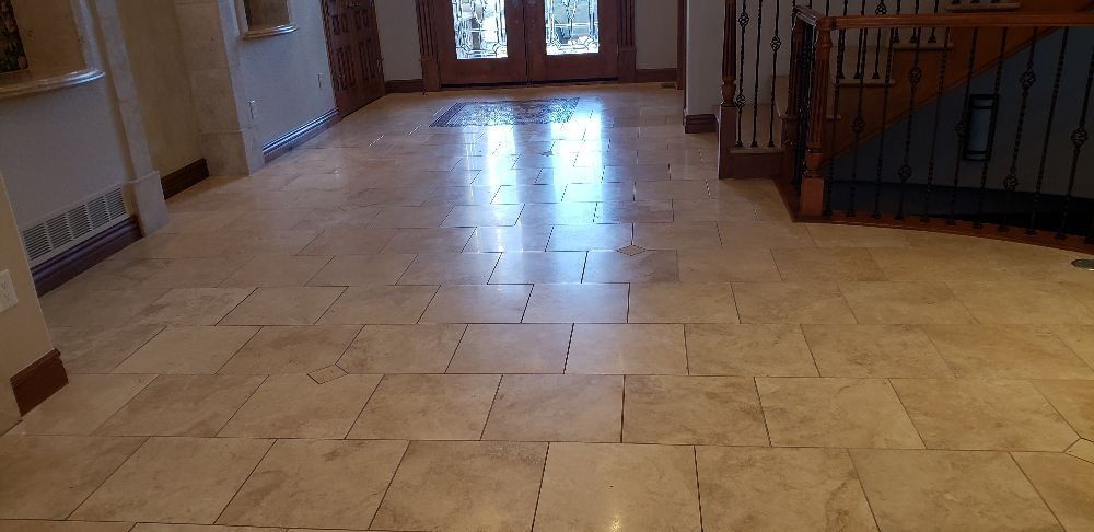 White tiled wall above beige marble baseboard and dark wood floor, with a cardboard box at right edge