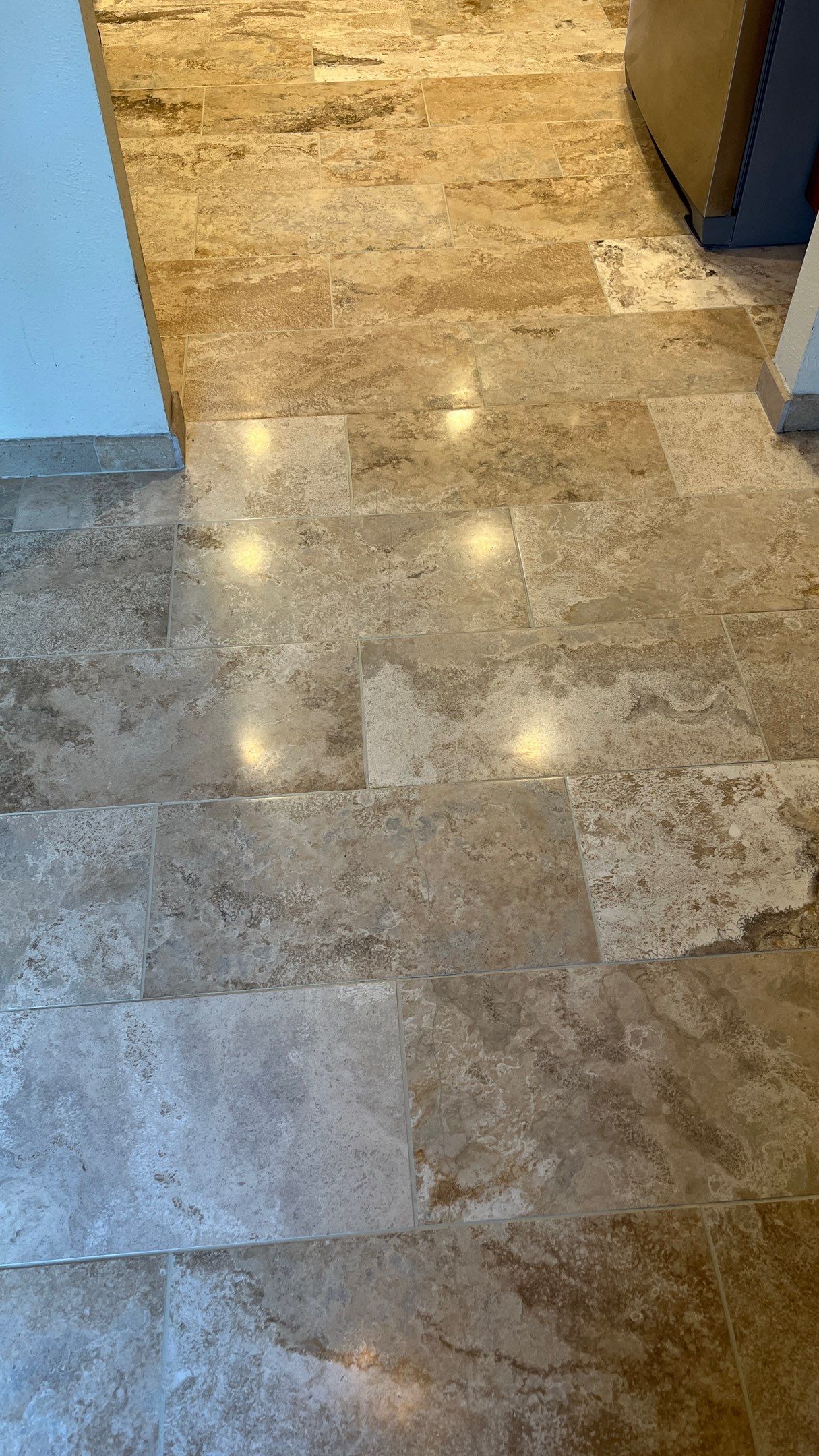 Polished marble floor with bright light reflections and a blue wall edge near a doorway
