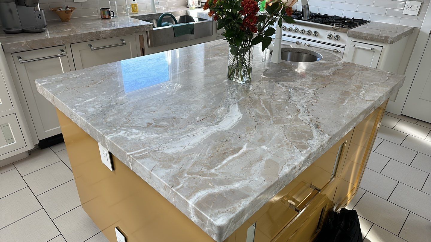White marble countertop with gray veining and bright ceiling light reflections in a room under renovation