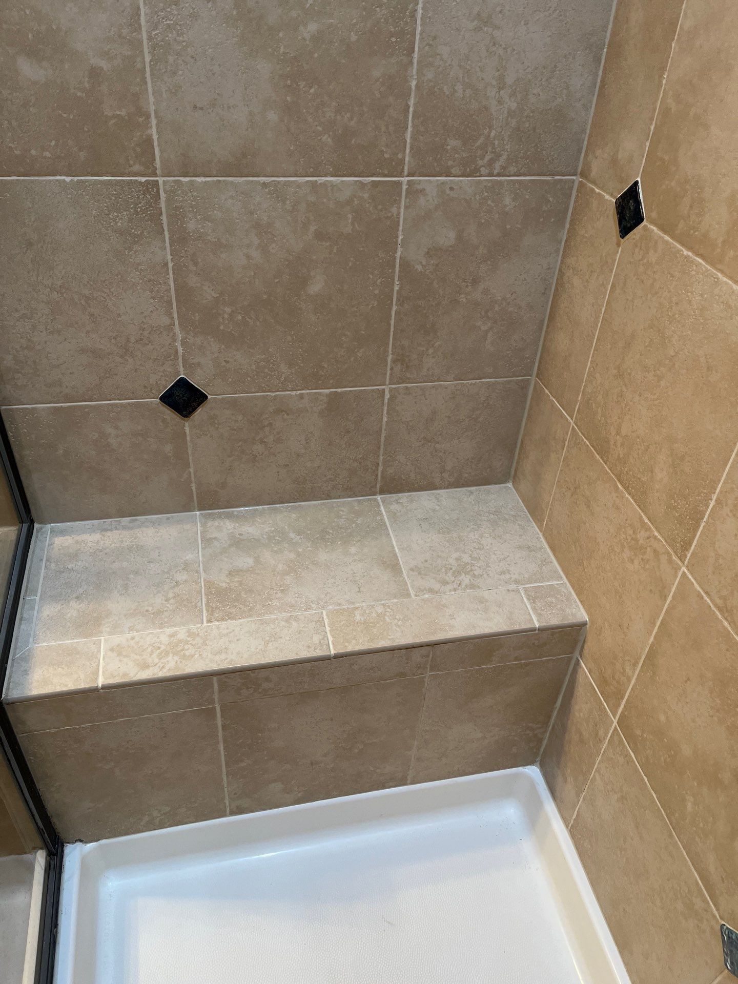 White tiled shower with built-in bench and two wall-mounted corner baskets.