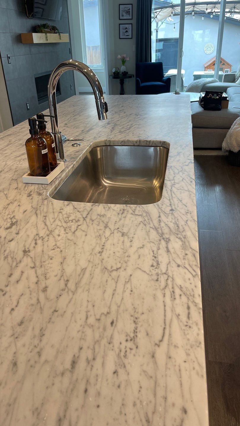 Marble kitchen island in a modern dining area with tables, chairs, and a dark wood floor