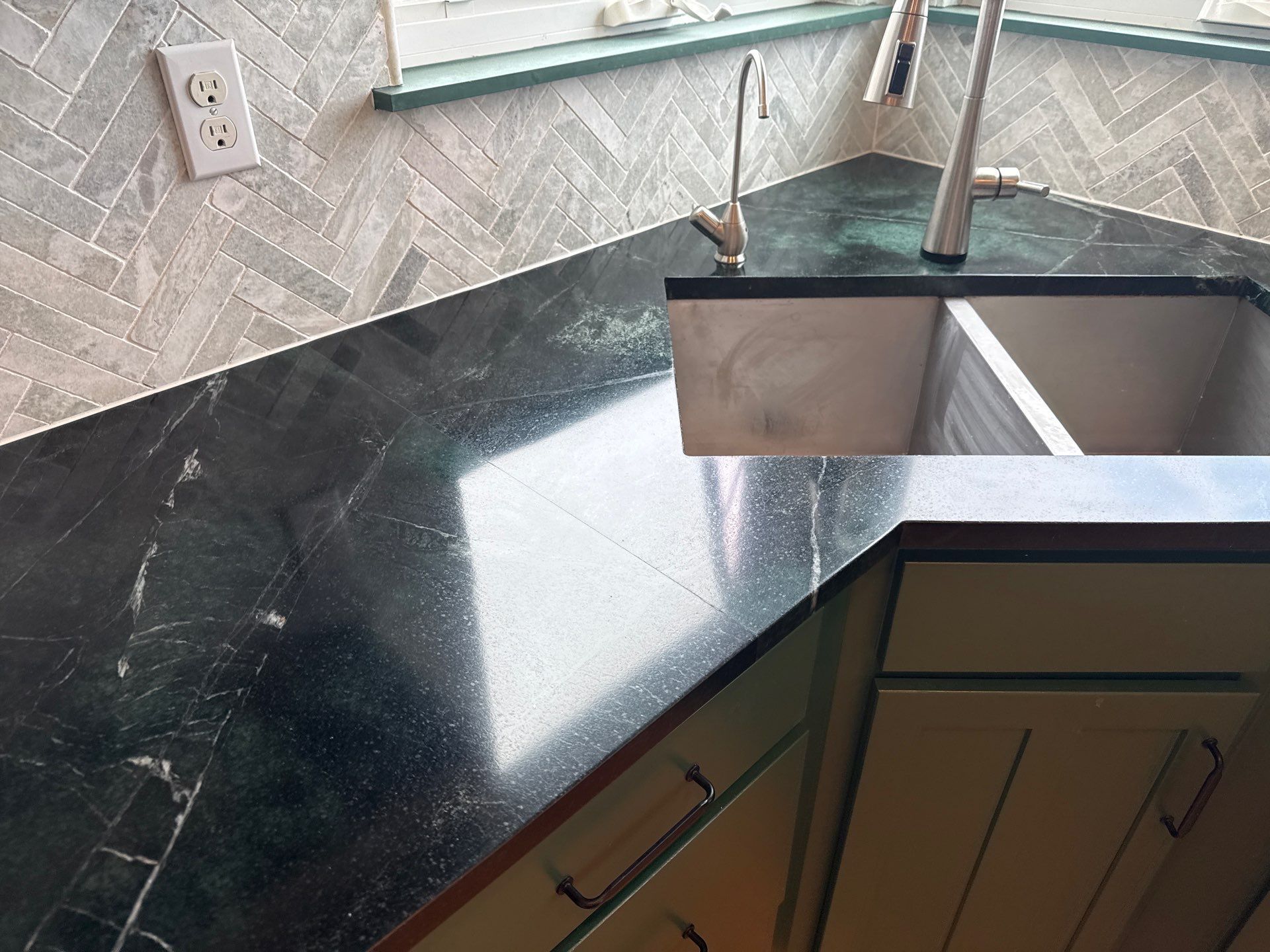 Modern kitchen with a long white island; a person cleans the floor in the background.