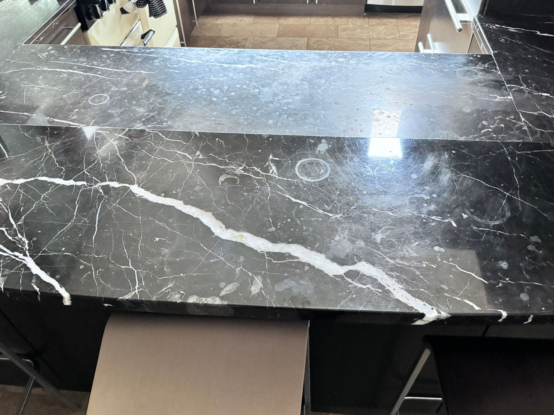 Kitchen counter with a marble-patterned surface and a dish rack in the background.