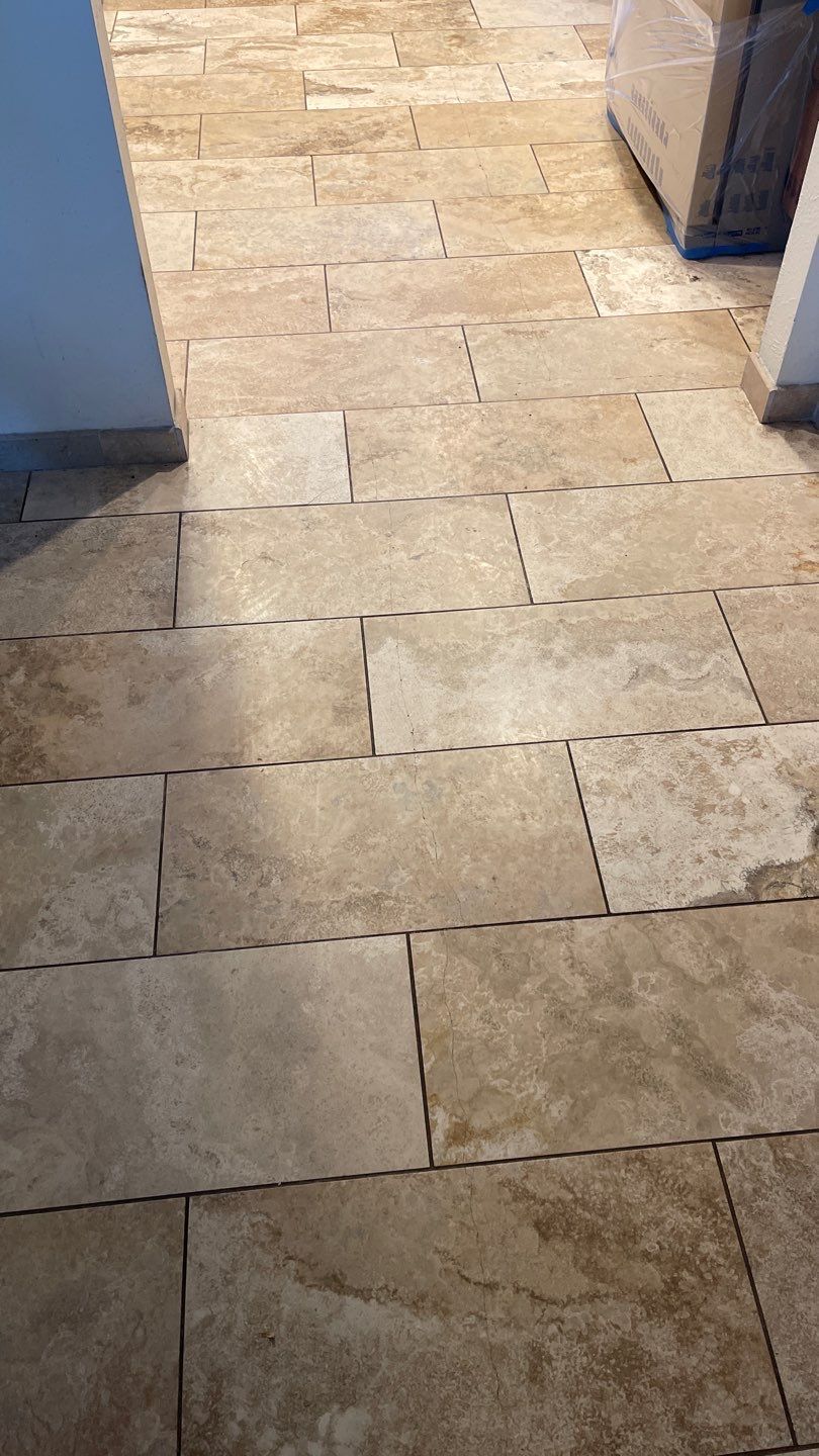 Empty tiled room with glossy floor, open glass doors, and daylight reflecting on the tiles