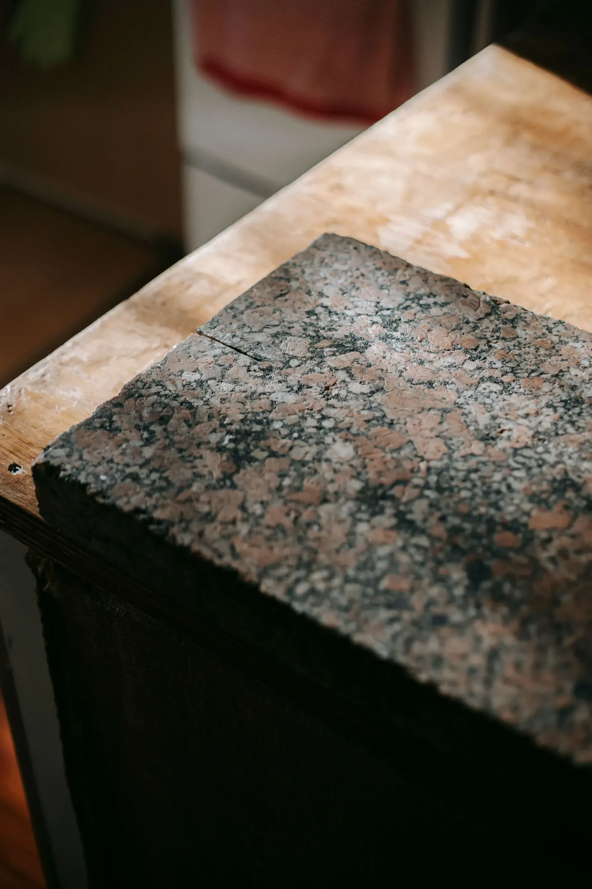 Close-up of a speckled granite countertop corner beside a tan stone surface.