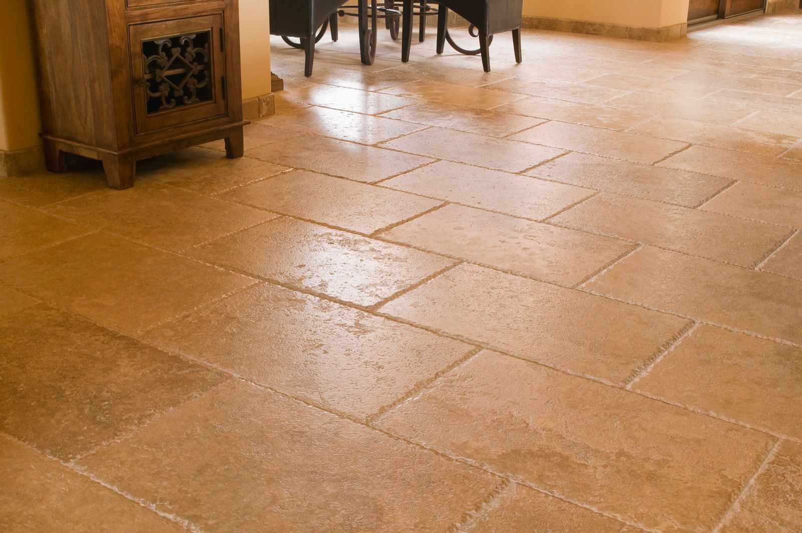 Terracotta-tiled floor in a warmly lit room with wooden furniture along the edge.