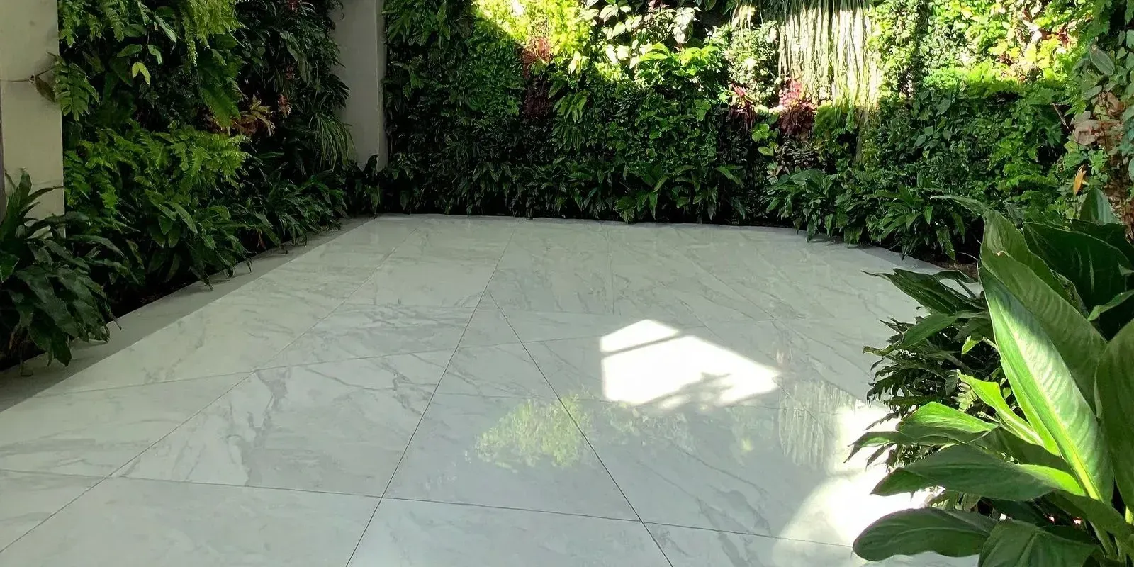 Empty stone patio bordered by lush green tropical plants and shrubs