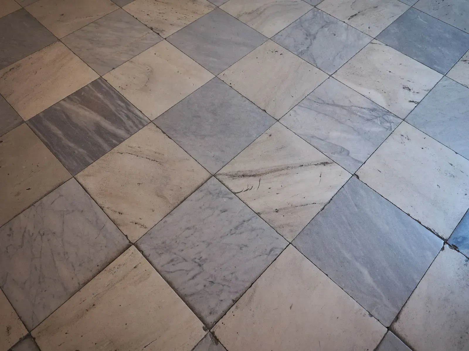 Diagonal pattern of gray and beige marble floor tiles in a checkerboard layout
