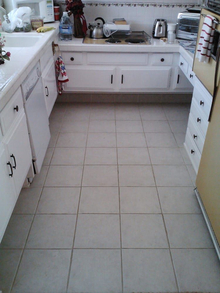 A kitchen with white cabinets and a tiled floor