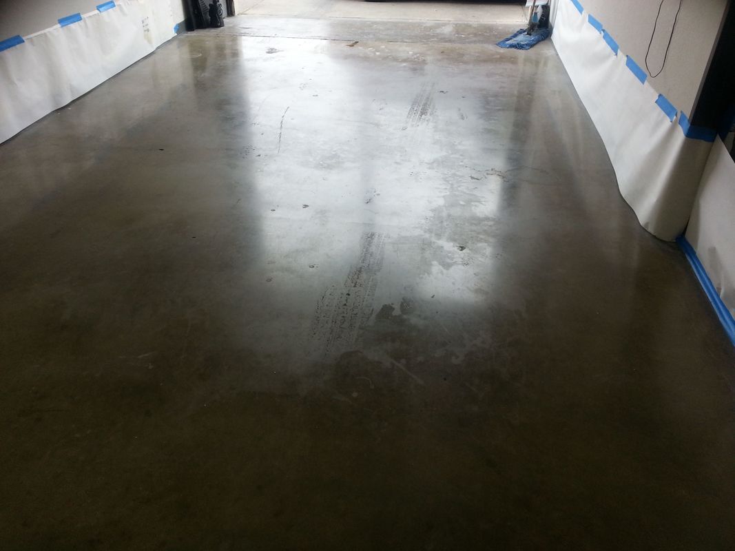 A concrete floor in a garage with blue tape on it.