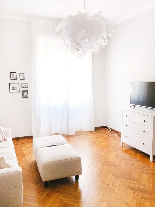 A living room with a couch , ottoman , television and dresser.