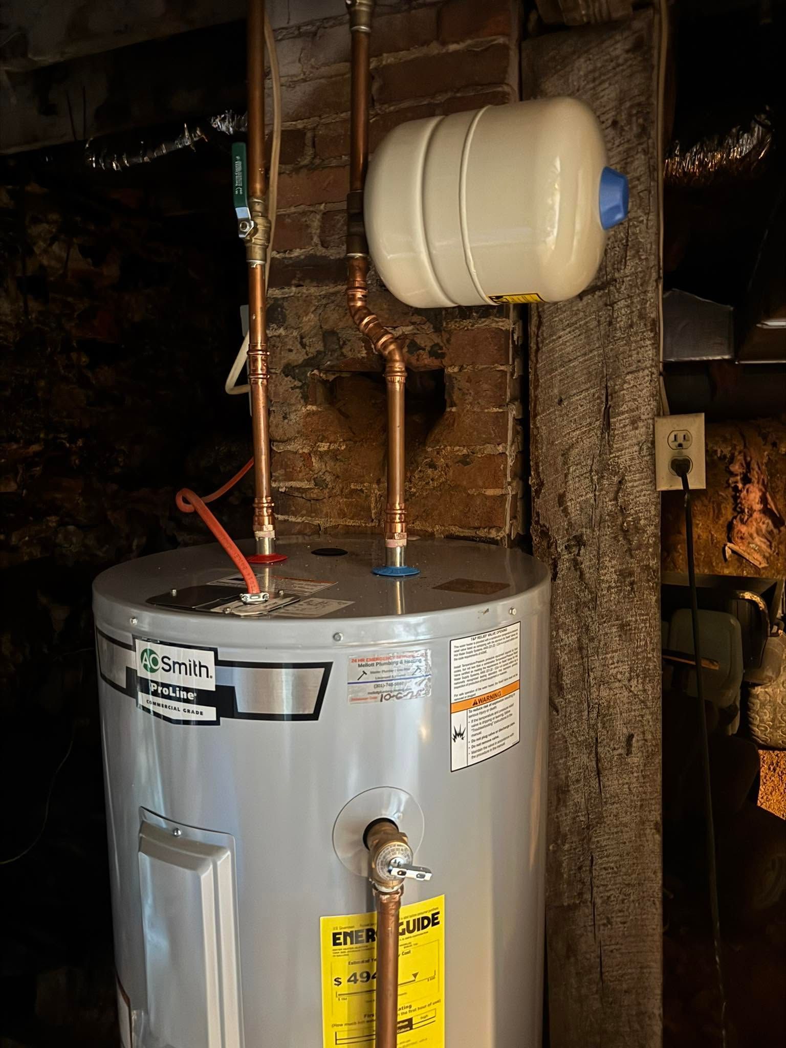 Old water heater with pipes and expansion tank in a dim basement or utility room
