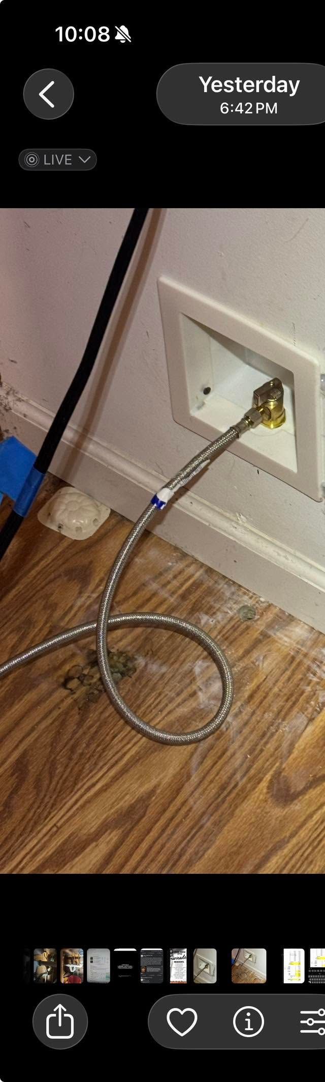 Coiled white cable plugged into a wall outlet beside a baseboard on a hardwood floor.
