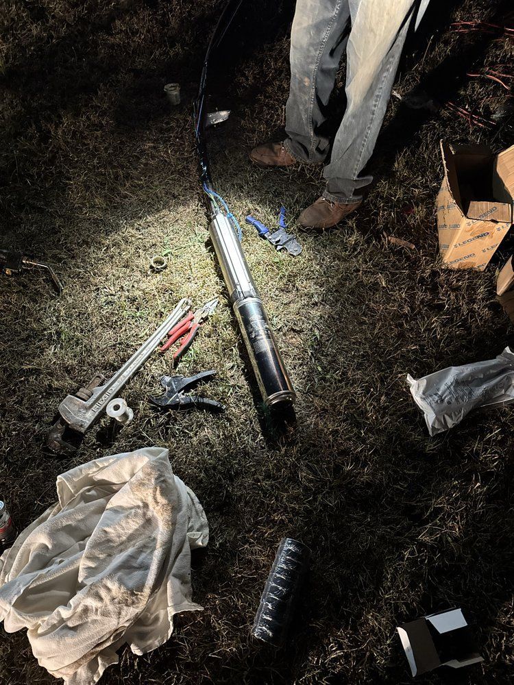 Person standing by a long metal tool and scattered equipment on dark ground at night