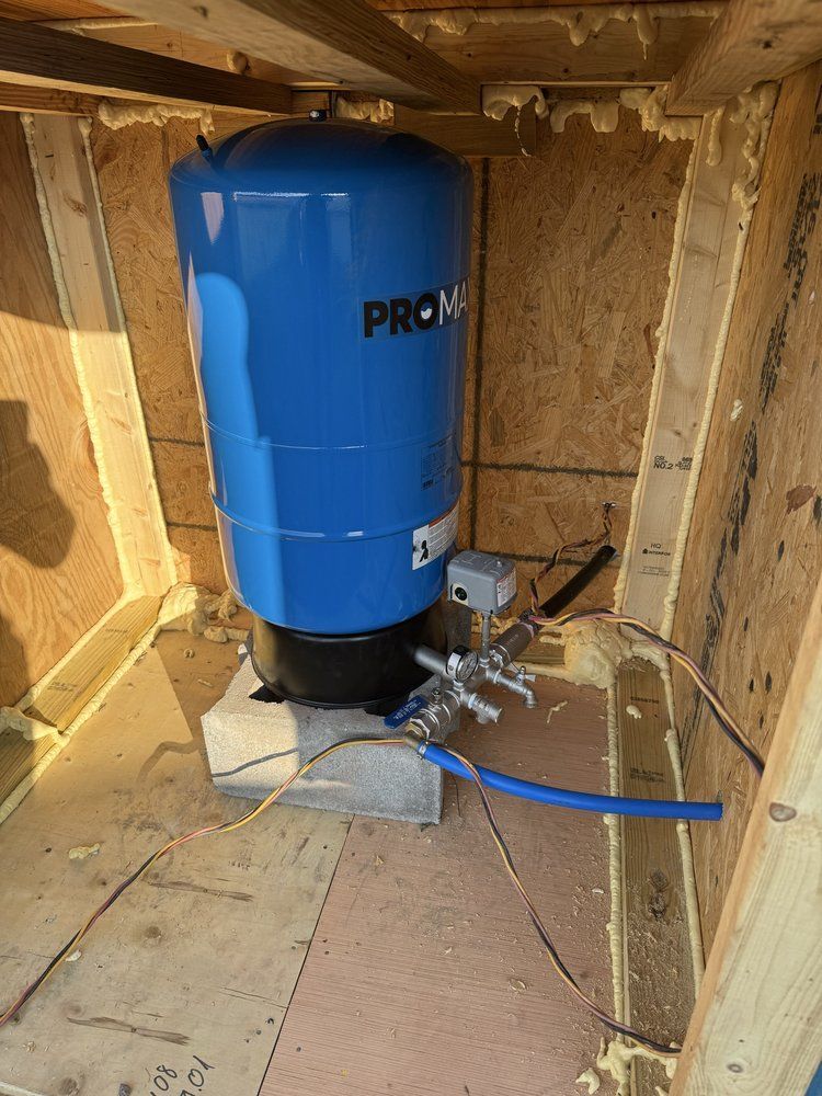 Blue water softener tank with plumbing inside a wooden cabinet