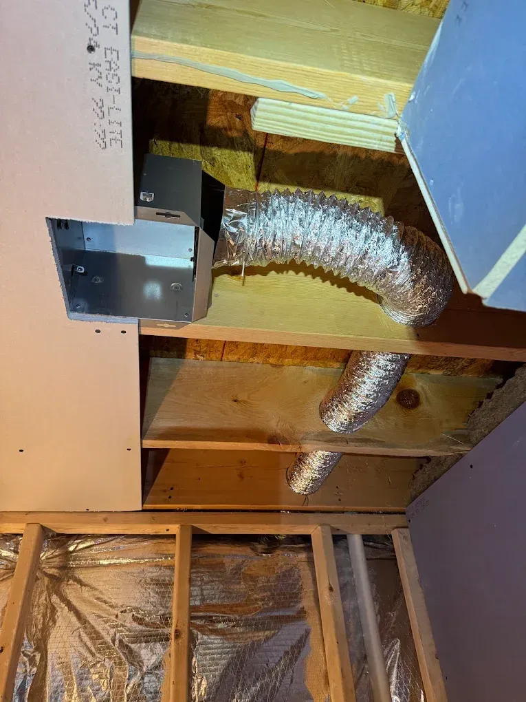 A water tank is sitting next to a pipe in a basement.